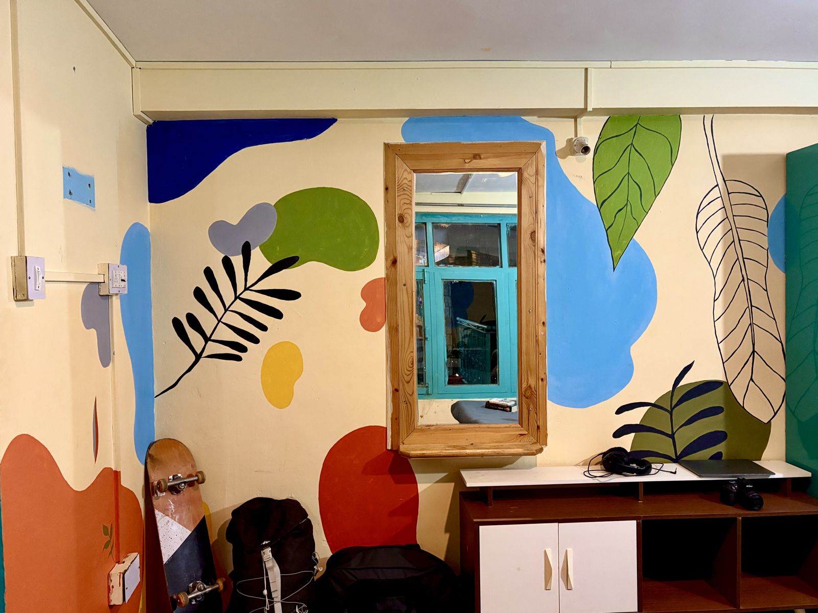 Colourful painted mural wall with a wooden mirror at Misfits
